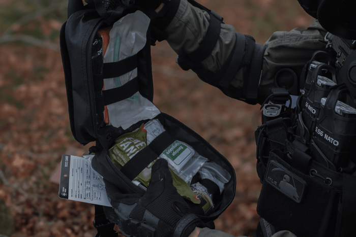 Flat lay of low-profile FlareSyn trauma kit components on a grey suit jacket, showcasing discreet urban emergency preparedness.